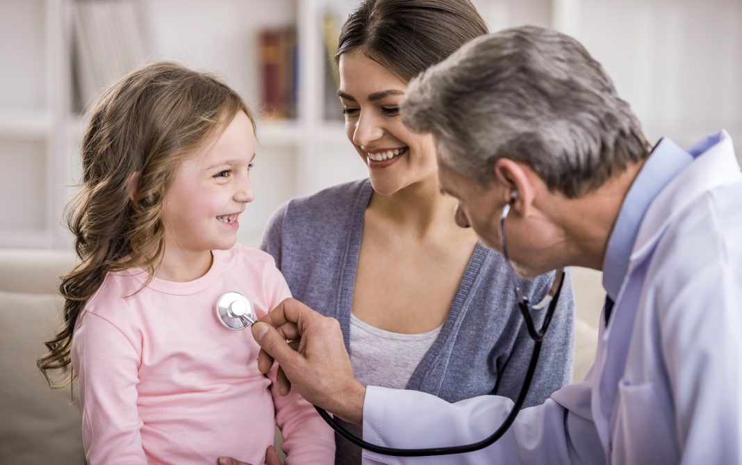 Pediatrician checks breath stethoscope a little girl in the arms of mother.